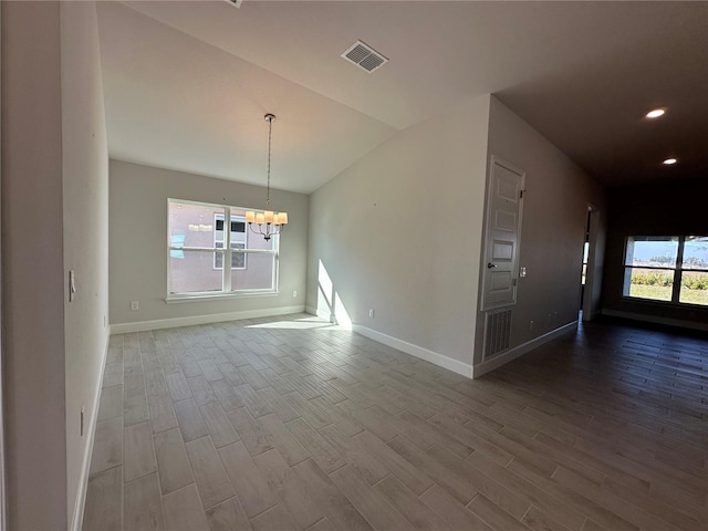 interior space featuring a healthy amount of sunlight, wood finished floors, visible vents, and an inviting chandelier