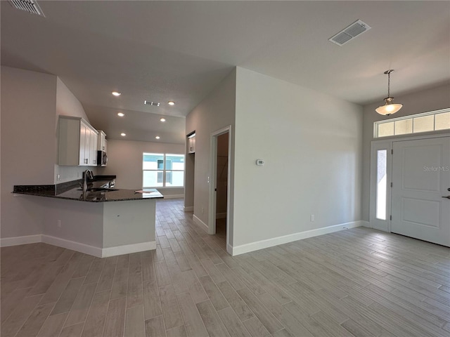 foyer with light wood-type flooring, visible vents, and baseboards