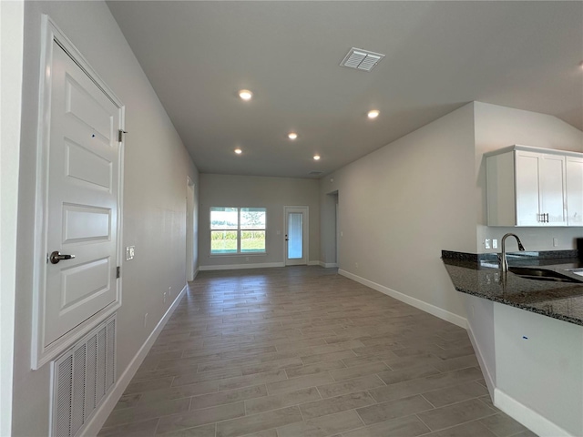 interior space featuring dark stone counters, a sink, visible vents, and white cabinets