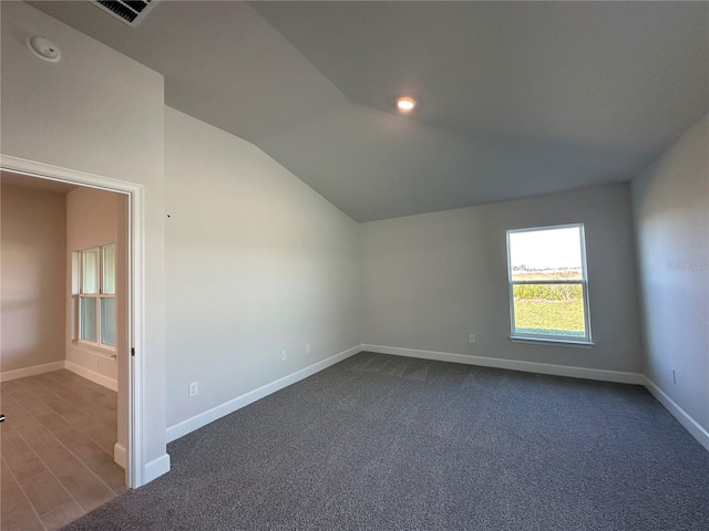 unfurnished room featuring carpet floors, lofted ceiling, visible vents, and baseboards