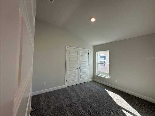 empty room featuring lofted ceiling, baseboards, dark carpet, and recessed lighting