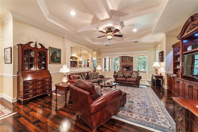 living room with ceiling fan, dark hardwood / wood-style flooring, coffered ceiling, a fireplace, and crown molding