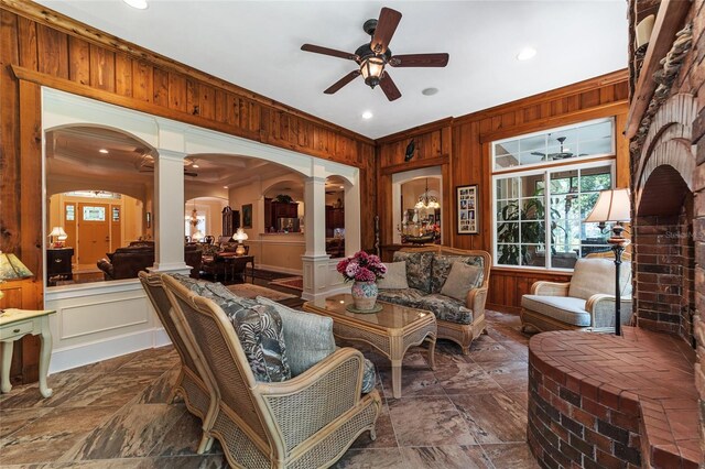 interior space with ceiling fan, decorative columns, and wood walls