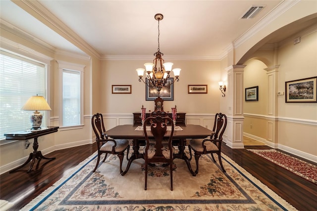 dining space featuring dark hardwood / wood-style floors, crown molding, decorative columns, and an inviting chandelier