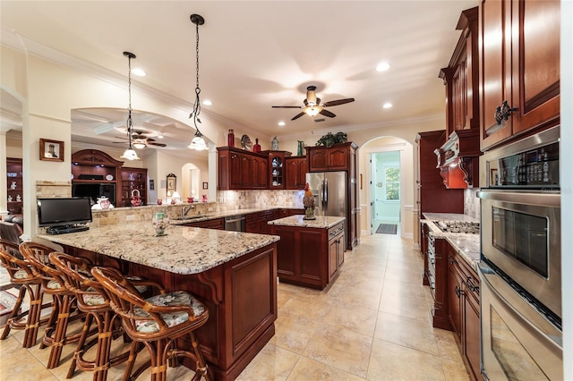 kitchen with backsplash, decorative light fixtures, stainless steel appliances, ceiling fan, and kitchen peninsula