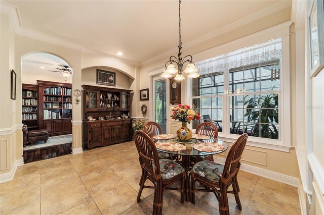 dining space with light hardwood / wood-style floors, ceiling fan with notable chandelier, and crown molding