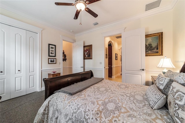 carpeted bedroom with a closet, ceiling fan, and ornamental molding