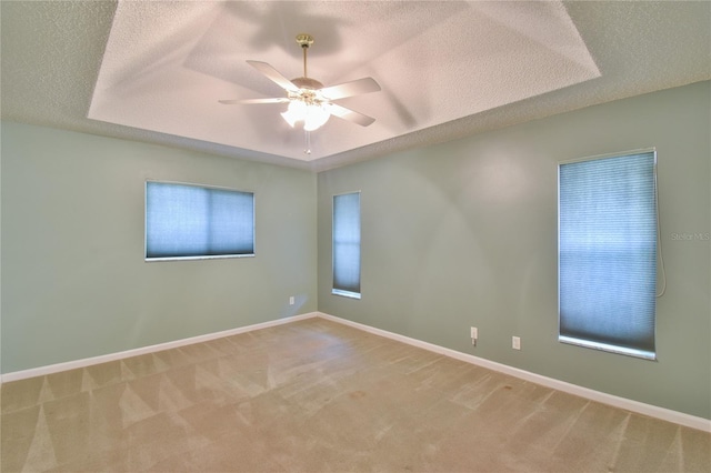 carpeted spare room featuring ceiling fan, a raised ceiling, and a textured ceiling