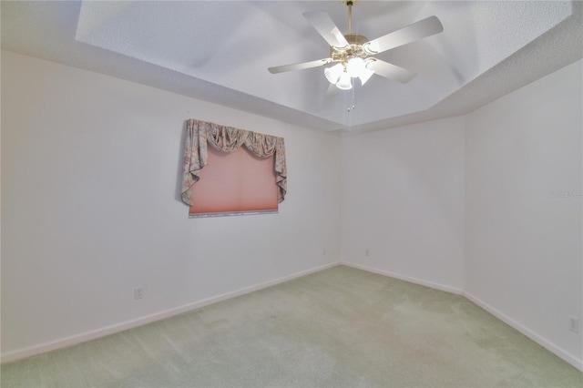 carpeted empty room featuring ceiling fan, a raised ceiling, and a textured ceiling