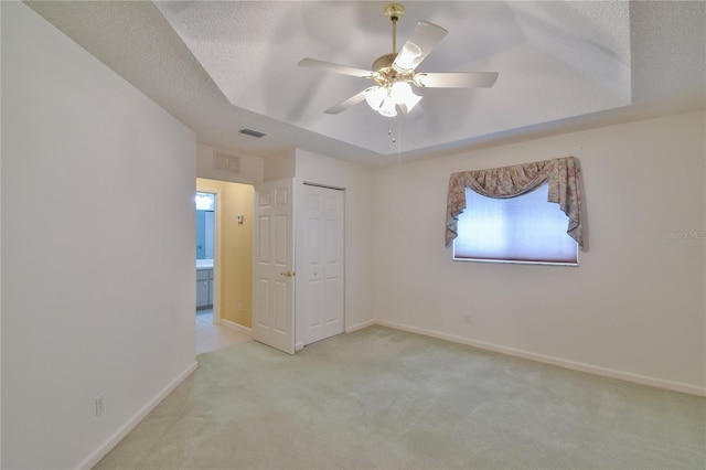 carpeted spare room with a tray ceiling, ceiling fan, and a textured ceiling