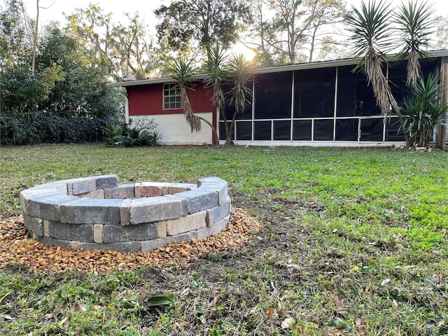 view of yard with an outdoor fire pit and a sunroom