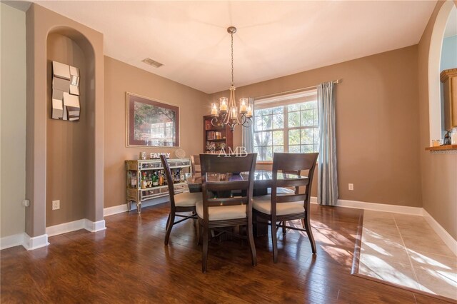 dining room with dark hardwood / wood-style floors and a notable chandelier