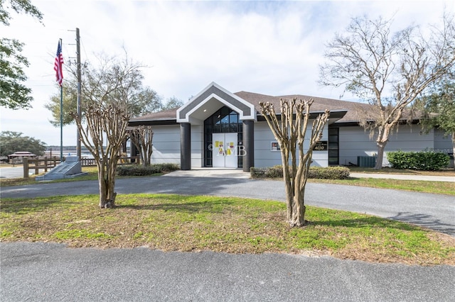 view of front of home featuring driveway, central AC unit, and a front yard