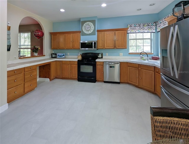 kitchen with brown cabinetry, plenty of natural light, stainless steel appliances, and a sink