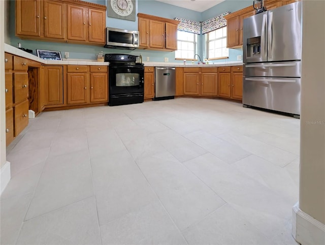 kitchen featuring a sink, brown cabinetry, stainless steel appliances, and light countertops