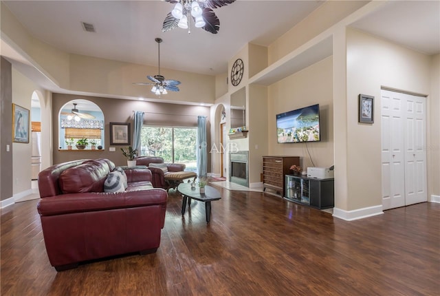 living area featuring a ceiling fan, visible vents, dark wood finished floors, and baseboards