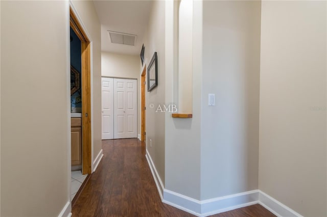 hallway featuring wood finished floors, visible vents, and baseboards