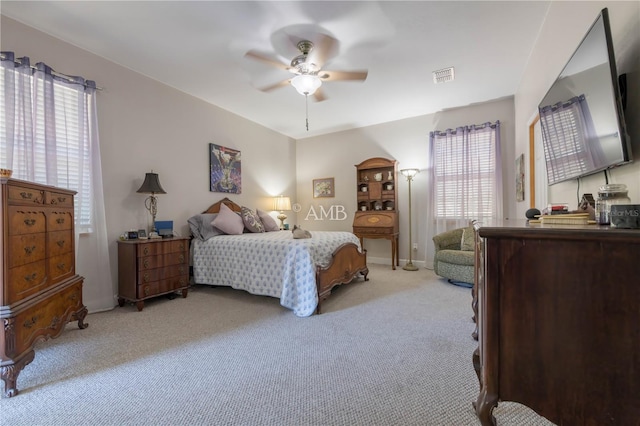 bedroom with light colored carpet, visible vents, and ceiling fan