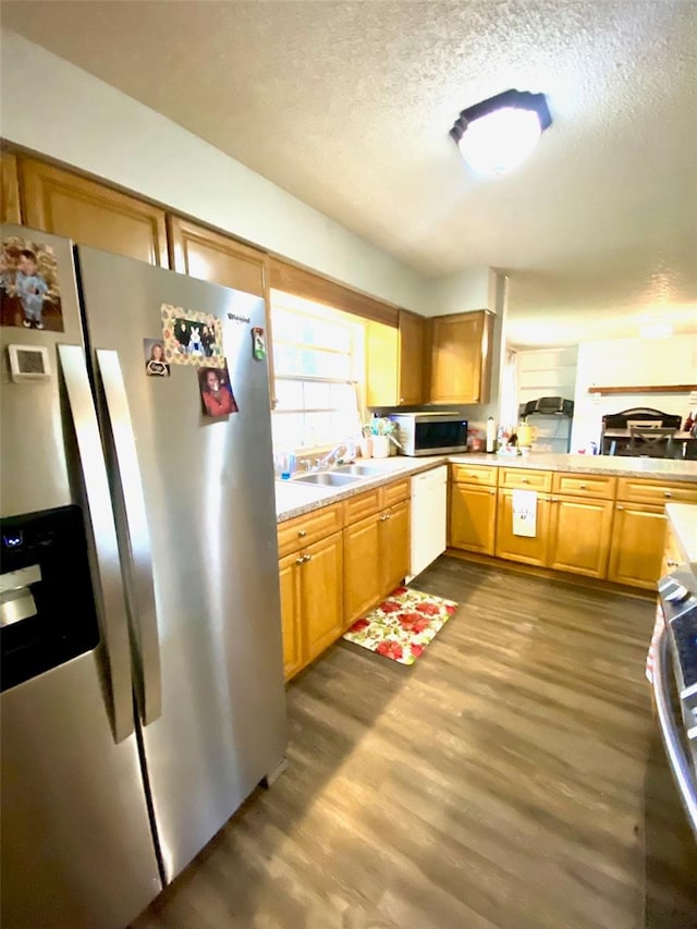 kitchen with hardwood / wood-style floors, appliances with stainless steel finishes, sink, and a textured ceiling