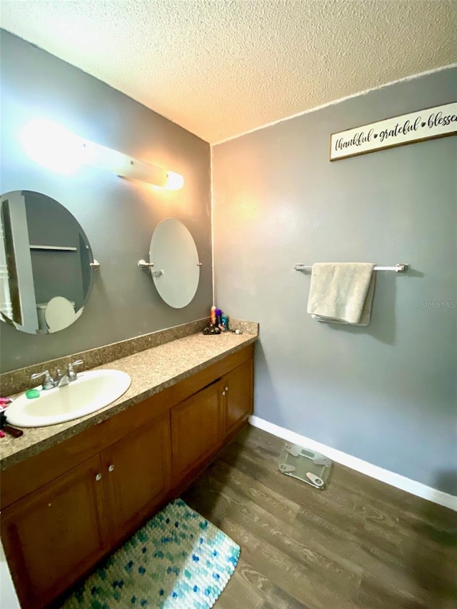 bathroom with a textured ceiling, vanity, and hardwood / wood-style floors