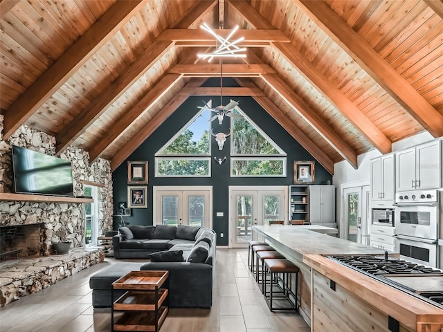 living room featuring beam ceiling, french doors, an inviting chandelier, high vaulted ceiling, and wood ceiling