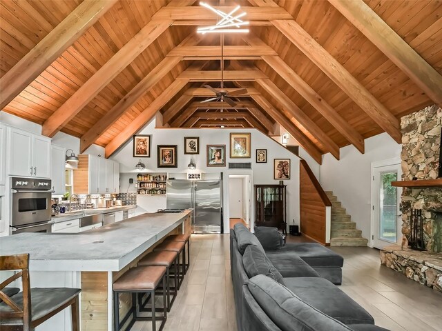 living room featuring beam ceiling, light tile patterned floors, wooden ceiling, and high vaulted ceiling