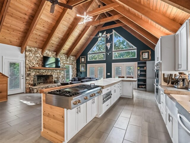 kitchen featuring high vaulted ceiling, french doors, beamed ceiling, white cabinetry, and stainless steel appliances