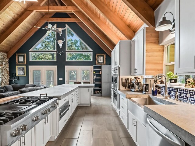 kitchen featuring white cabinetry, french doors, stainless steel appliances, high vaulted ceiling, and beamed ceiling