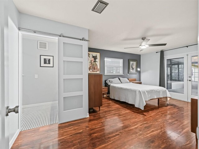 bedroom featuring ceiling fan, dark hardwood / wood-style floors, a barn door, and access to outside