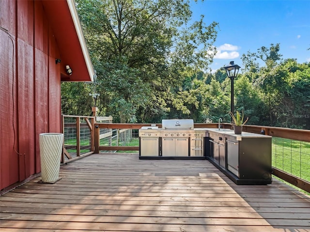 wooden deck with an outdoor kitchen, area for grilling, and sink