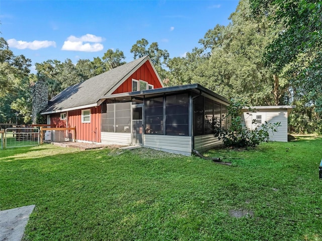 back of house featuring a sunroom and a lawn