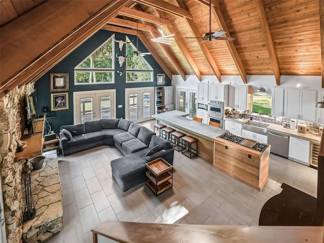 living room with beam ceiling, ceiling fan, french doors, wooden ceiling, and high vaulted ceiling