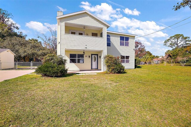 rear view of property featuring a balcony and a yard