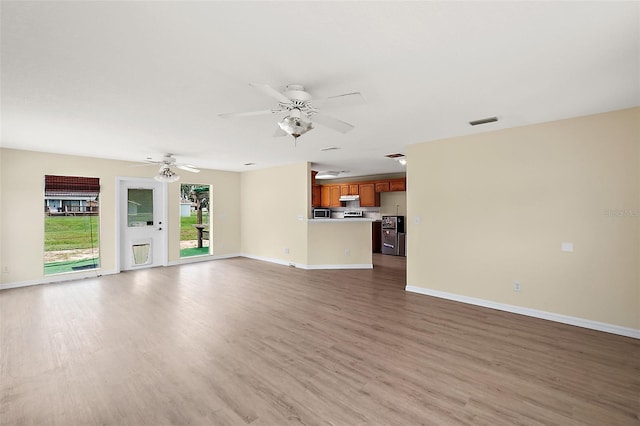 unfurnished living room featuring a ceiling fan, visible vents, baseboards, and wood finished floors