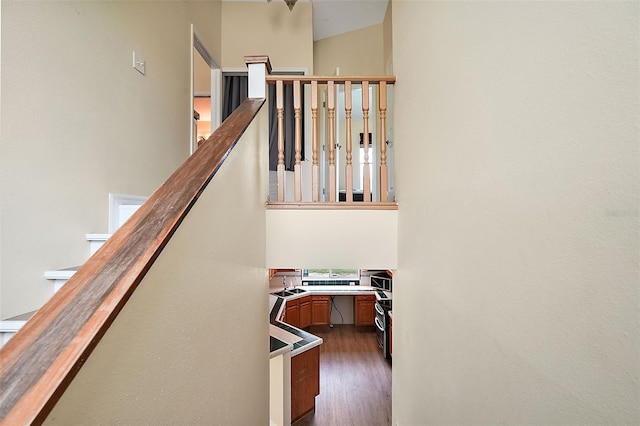 staircase with a high ceiling, wood finished floors, and built in desk