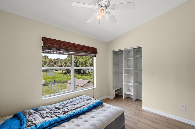 bedroom featuring ceiling fan, light wood-type flooring, vaulted ceiling, and a closet