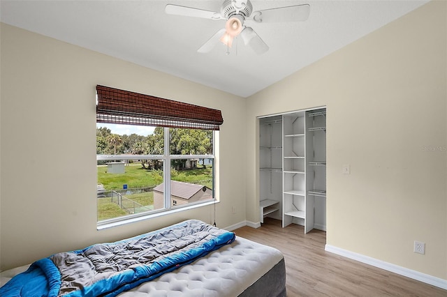 bedroom featuring lofted ceiling, a closet, a ceiling fan, light wood-type flooring, and baseboards