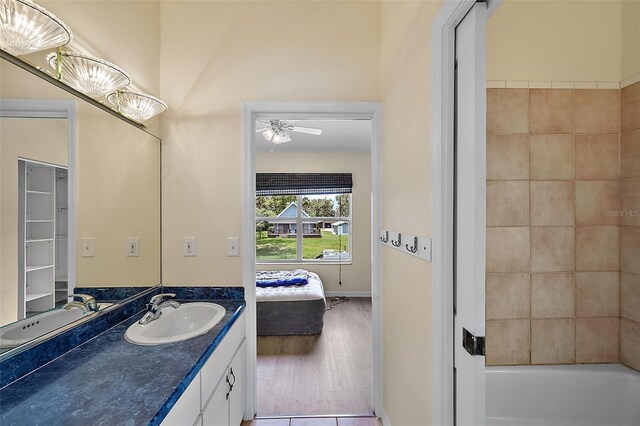 bathroom with ceiling fan,  shower combination, hardwood / wood-style flooring, and vanity