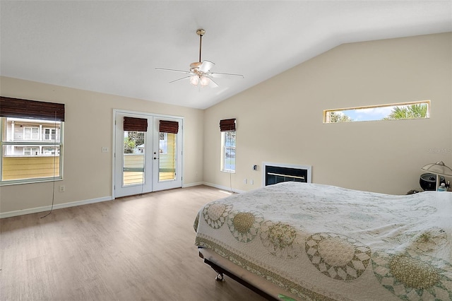 bedroom featuring access to exterior, french doors, a fireplace, light wood finished floors, and lofted ceiling