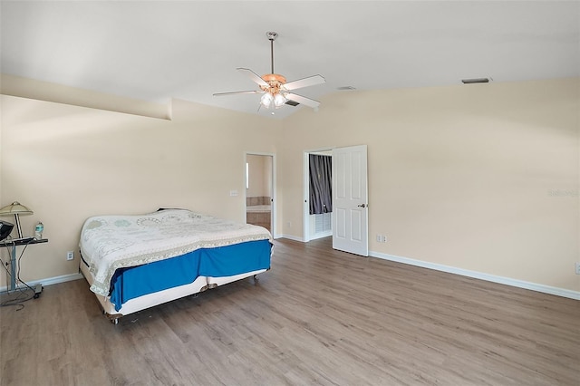 bedroom featuring visible vents, baseboards, vaulted ceiling, and wood finished floors