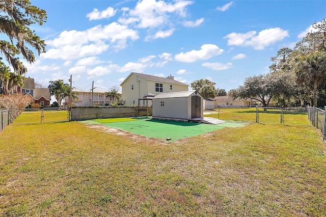 view of yard featuring a storage shed, a gate, fence, a residential view, and an outdoor structure