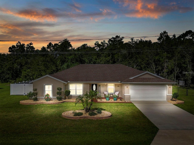 ranch-style home featuring a garage and a lawn