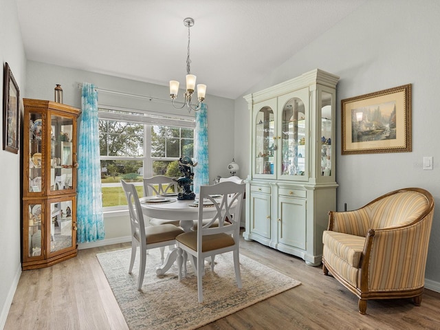 dining area featuring light wood-type flooring, vaulted ceiling, and an inviting chandelier