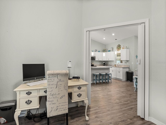 home office featuring hardwood / wood-style floors, sink, and vaulted ceiling