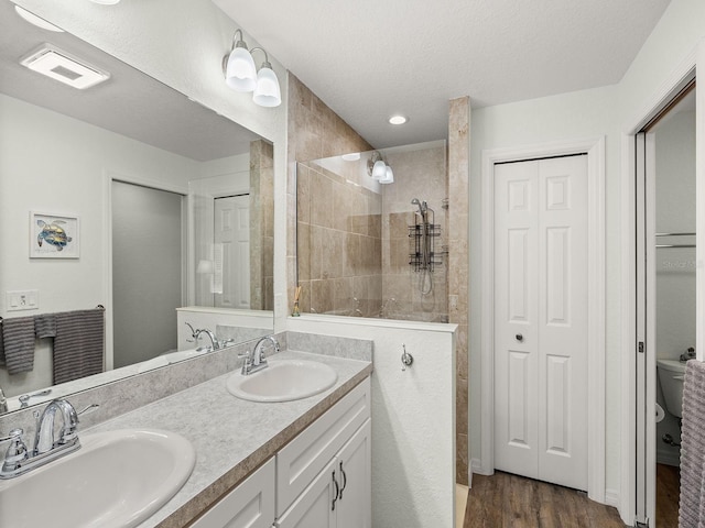 bathroom with vanity, toilet, wood-type flooring, and a tile shower