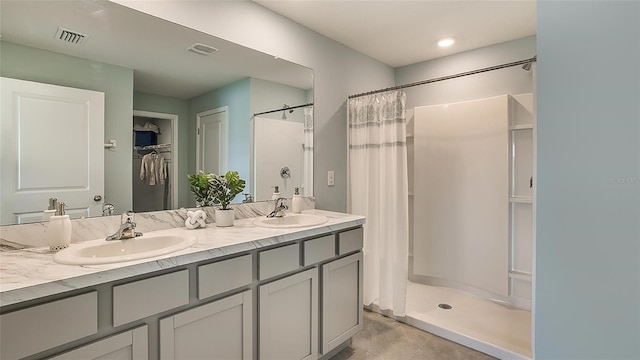 bathroom with tile patterned flooring, walk in shower, and dual bowl vanity