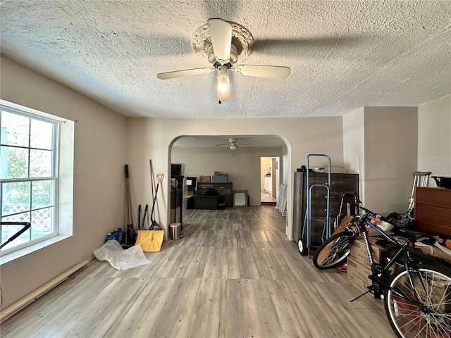 misc room with a wealth of natural light, a textured ceiling, light hardwood / wood-style flooring, and ceiling fan