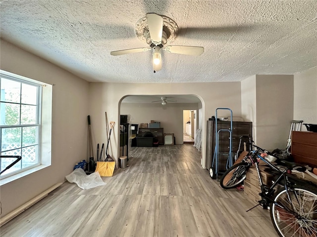 exercise area with ceiling fan, hardwood / wood-style floors, and a textured ceiling