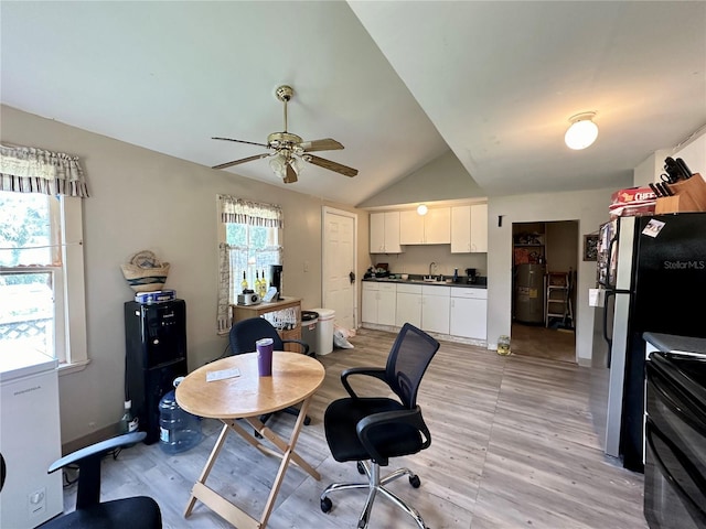 dining space featuring lofted ceiling, sink, water heater, ceiling fan, and light wood-type flooring