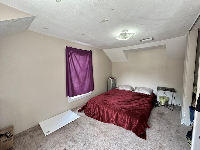 bedroom featuring carpet, vaulted ceiling, and a textured ceiling